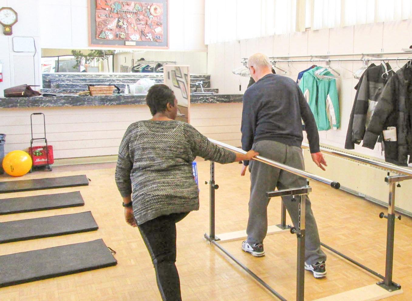 A physiotherapist helps a senior with their exercises