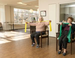 Two senior women exercising with stretching bands