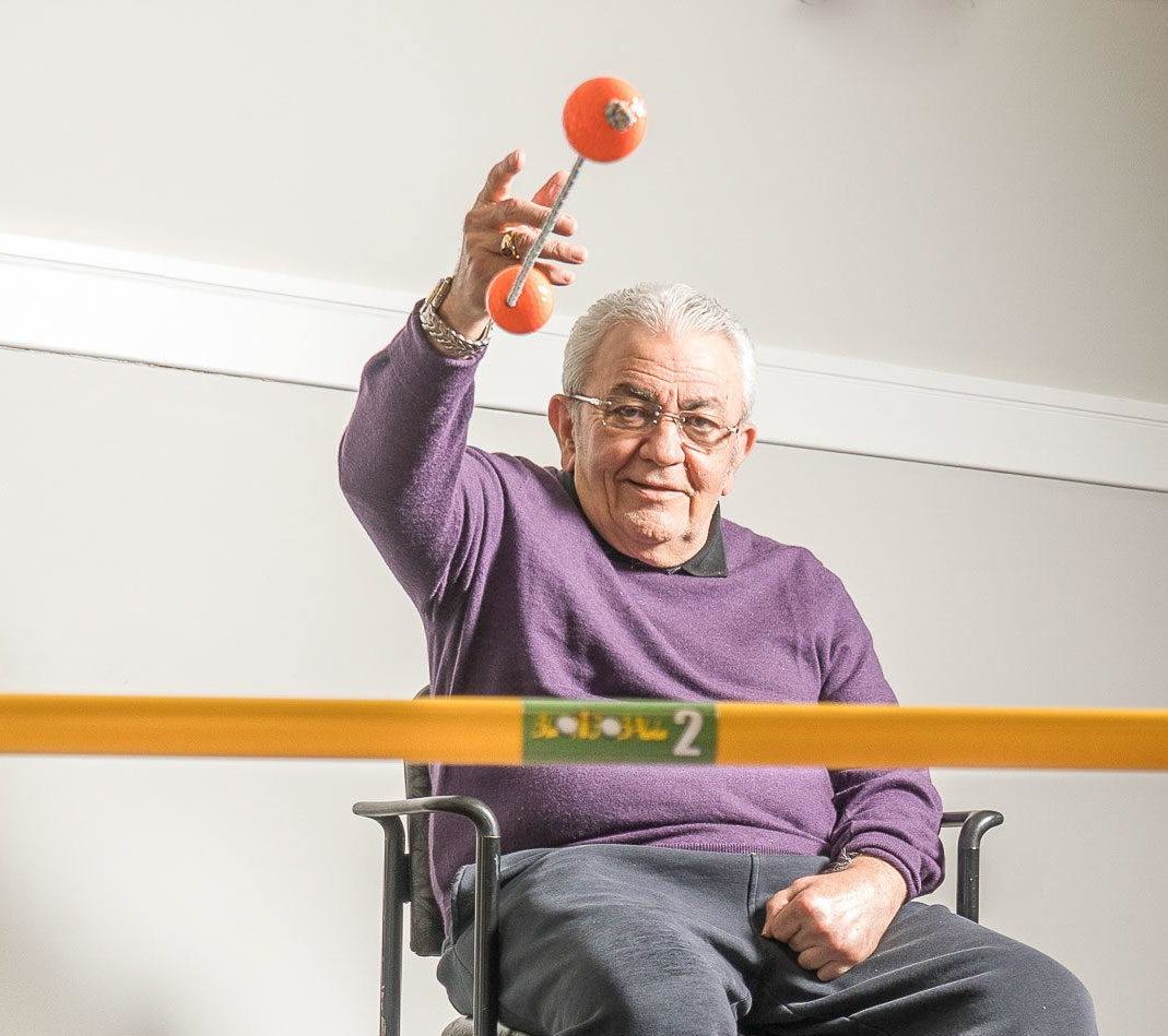A senior sat in a chair playing with a ball