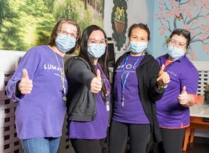 Four Lumacare staff members in mask, giving the camera a thumbs up