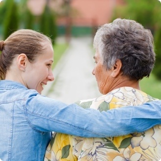A caregiver walking with arms over a seniors shoulder